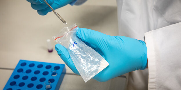 Chemiker mit blauen Handschuhen mit Pipette und Reagenzglas Chemiker mit blauen Handschuhen mit Pipette und Reagenzglas