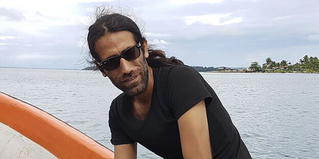 Ein Mann mit Sonnenbrille sitzt auf einem Boot Ein Mann mit Sonnenbrille sitzt auf einem Boot