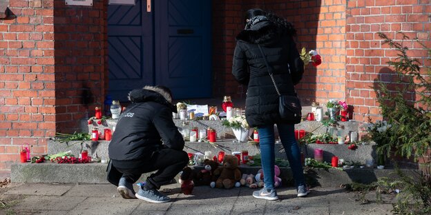 Ein Mann und eine Frau vor einem Meer aus Kerzen und Blumen – die an ein totes Mädchen erinnern Ein Mann und eine Frau vor einem Meer aus Kerzen und Blumen – die an ein totes Mädchen erinnern
