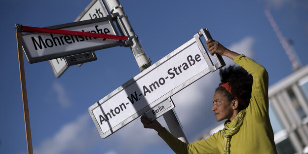 Eine Frau ersetzt das Straßenschild "Mohrenstraße" durch "Anton-W-Amo-Straße" Eine Frau ersetzt das Straßenschild "Mohrenstraße" durch "Anton-W-Amo-Straße"