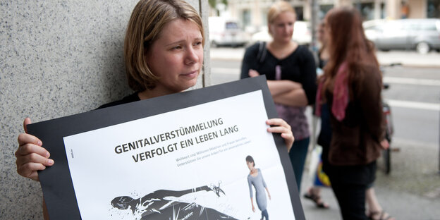 Demonstrantin hält Schild mit Aufschrift: "Genitalverstümmelung verfolgt ein Leben lang" Demonstrantin hält Schild mit Aufschrift: "Genitalverstümmelung verfolgt ein Leben lang"