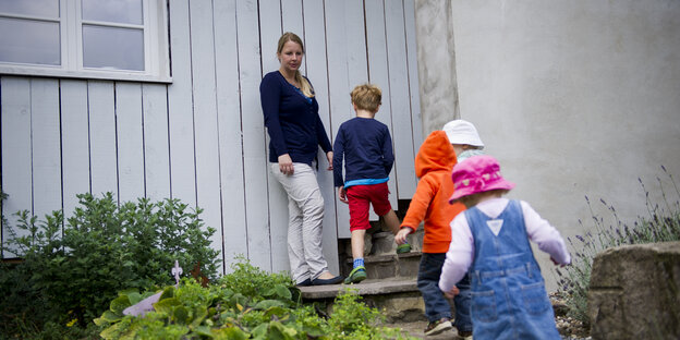 Eine Tagesmutter wartet an einem Hauseingang auf vier Kinder.