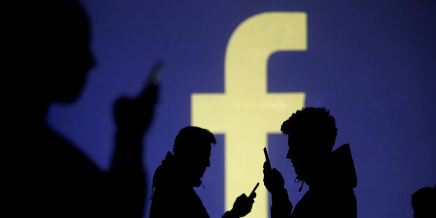 Menschen mit Smartphones vor dem Facebook-Zeichen. Menschen mit Smartphones vor dem Facebook-Zeichen.