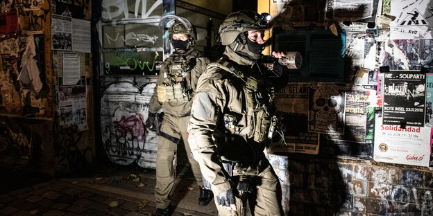 Ein vermummter SEK-Polizist steht nachts vor einem Hauseingang Ein vermummter SEK-Polizist steht nachts vor einem Hauseingang