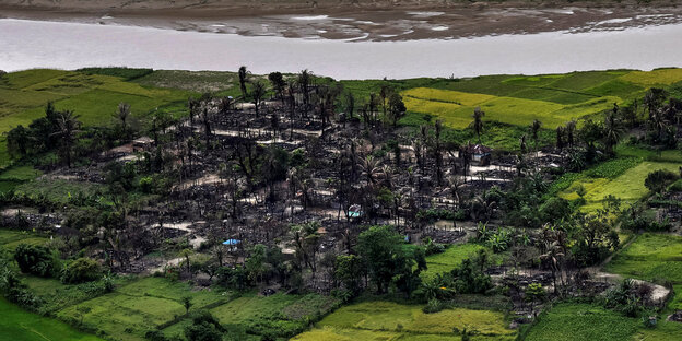 In Myanmar ist ein niederbegranntes Dorf von grünen Feldern umgeben In Myanmar ist ein niederbegranntes Dorf von grünen Feldern umgeben
