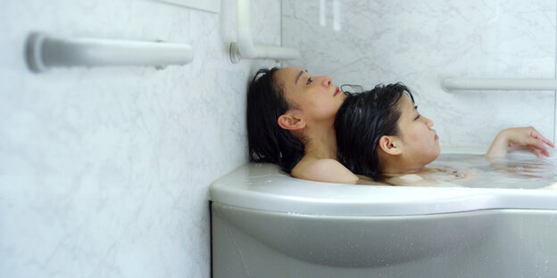 Mutter und Tochter liegen zusammen in der Badewanne Mutter und Tochter liegen zusammen in der Badewanne