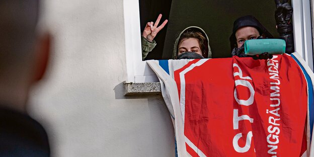Zwei vermummte Jugendliche schauen aus einem Fenster und zeigen das Victory-Zeichen. Zwei vermummte Jugendliche schauen aus einem Fenster und zeigen das Victory-Zeichen.
