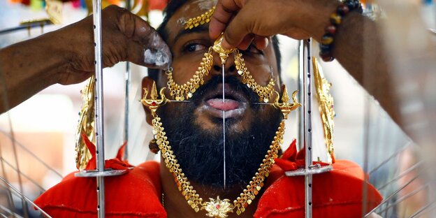Ein Mann mit viel Schmuck hat eine Nadel durch seine Zunge gesteckt Ein Mann mit viel Schmuck hat eine Nadel durch seine Zunge gesteckt