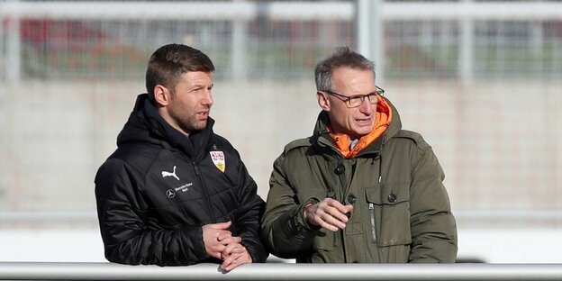 Zwei Männer stehen am Spielfeldrand Zwei Männer stehen am Spielfeldrand