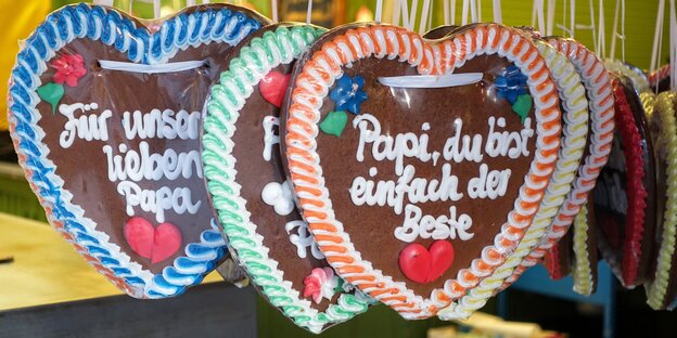 Lebkuchenherzen hängen an Schnüren. Auf einem steht: „Papi, du bist einfach der Beste“ Lebkuchenherzen hängen an Schnüren. Auf einem steht: „Papi, du bist einfach der Beste“