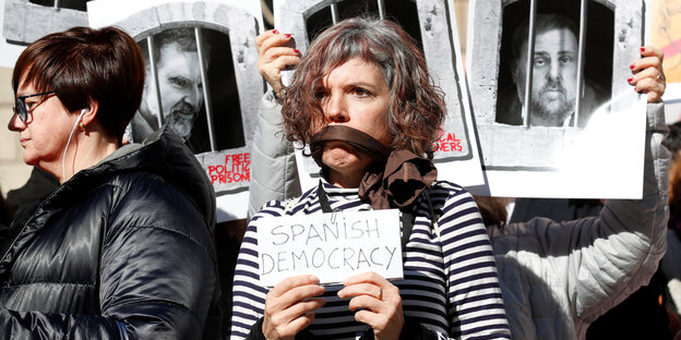 Bei einem Protest werden Fotos katalanischer Unabhängigkeitspolitiker gehalten und eine protestierende Frau hat ihren Mund überklebt Bei einem Protest werden Fotos katalanischer Unabhängigkeitspolitiker gehalten und eine protestierende Frau hat ihren Mund überklebt