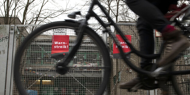 fahrrad fährt vorbei an verschlossener kindergartentür, an der ein schild hängt. darauf steht warnstreik fahrrad fährt vorbei an verschlossener kindergartentür, an der ein schild hängt. darauf steht warnstreik