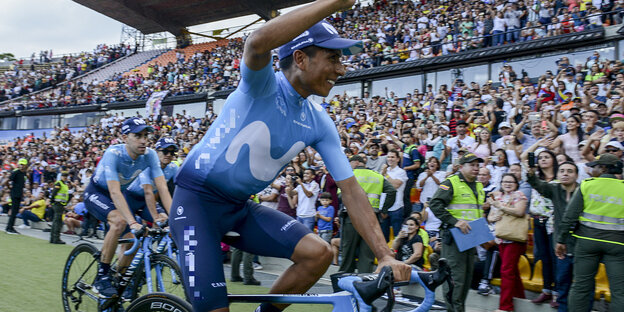 Der kolumbianische Radsportprofi Nairo Quintana sitzt auf einem Fahrad und winkt Fans auf einer Tribüne bei der Tour Colombia zu Der kolumbianische Radsportprofi Nairo Quintana sitzt auf einem Fahrad und winkt Fans auf einer Tribüne bei der Tour Colombia zu