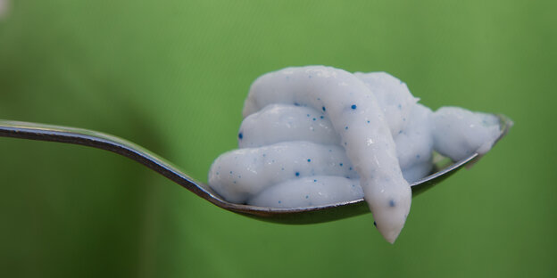 Ein Löffel mit einer Crème, in der Plastikkügelchen enthalten sind. Ein Löffel mit einer Crème, in der Plastikkügelchen enthalten sind.