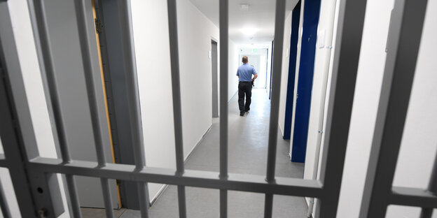 ein justizbeamter hinter vergitterter tür einer abschiebehafteinrichtung ein justizbeamter hinter vergitterter tür einer abschiebehafteinrichtung