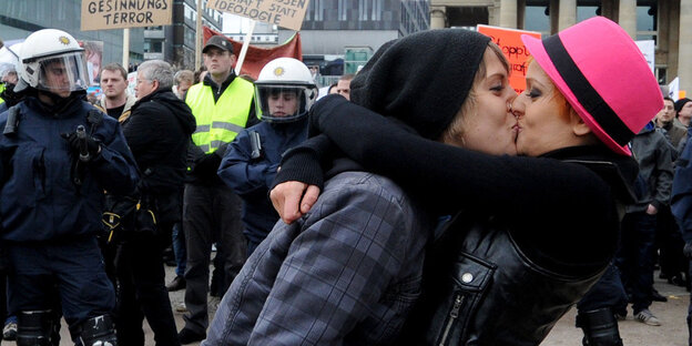 Zwei Menschen küssen sich vor einer Demo Zwei Menschen küssen sich vor einer Demo