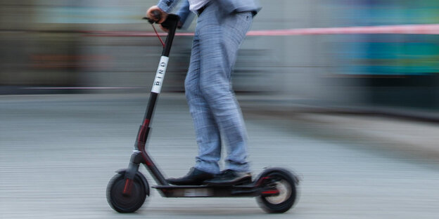 Ein Mann im Anzug auf einem e-Roller Ein Mann im Anzug auf einem e-Roller