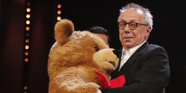 Ein Mann, Dieter Kosslick, mit einem großen Plüschbären Ein Mann, Dieter Kosslick, mit einem großen Plüschbären