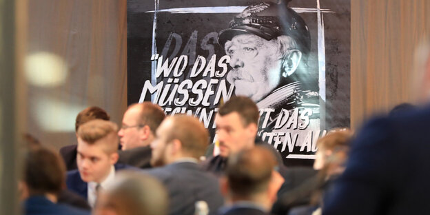 Männer in einem Sitzungssaal, auf einem großen Bild ist ein Foto von Bismarck zu sehen Männer in einem Sitzungssaal, auf einem großen Bild ist ein Foto von Bismarck zu sehen