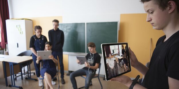 Ein Schüler hält ein Tablet in der Hand Ein Schüler hält ein Tablet in der Hand