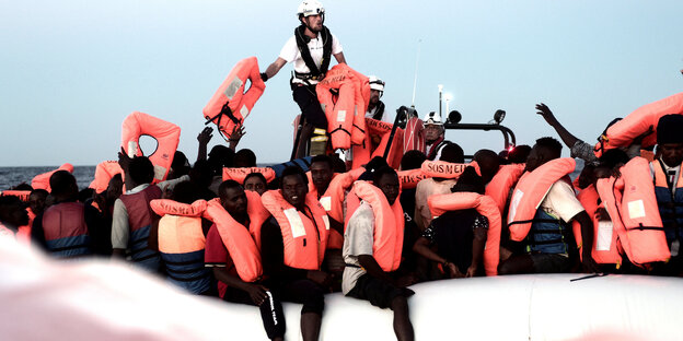 Menschen mit roten Rettungswesen auf einem Schlauchboot Menschen mit roten Rettungswesen auf einem Schlauchboot