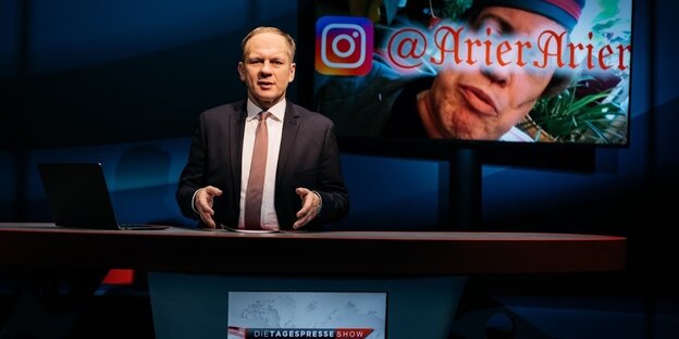 Ein österreichischer Nachrichtenmoderator, Paul Kraker, im Theater Rabenhof auf der Bühne in einer Art Nachrichtenstudio Ein österreichischer Nachrichtenmoderator, Paul Kraker, im Theater Rabenhof auf der Bühne in einer Art Nachrichtenstudio