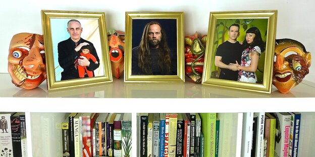 Ein weißes Buchregal, auf dem Bord stehen mehrere Fotos von Personen in goldenen Rahmen Ein weißes Buchregal, auf dem Bord stehen mehrere Fotos von Personen in goldenen Rahmen