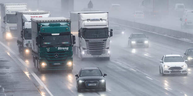 Mehrere Fahrzeuge, darunter auch Lkw, auf einer Autobahn bei Regen Mehrere Fahrzeuge, darunter auch Lkw, auf einer Autobahn bei Regen