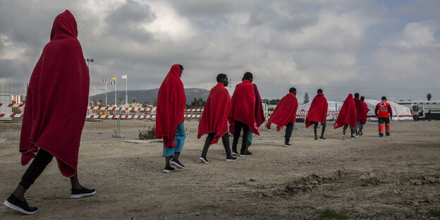 In rote Decken gehüllte, aus Seenot gerettete Flüchtlinge und Migrante sind in im Hafen Algeciras angekommen In rote Decken gehüllte, aus Seenot gerettete Flüchtlinge und Migrante sind in im Hafen Algeciras angekommen