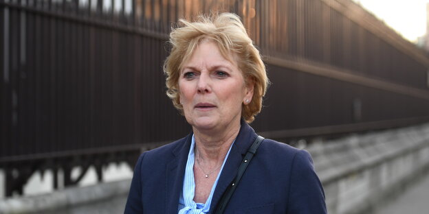 Anna Soubry, eine Frau mit blauem Jackett und blonden kurzen Haaren, läuft an einem hohen rostigen Zaun entlang Anna Soubry, eine Frau mit blauem Jackett und blonden kurzen Haaren, läuft an einem hohen rostigen Zaun entlang