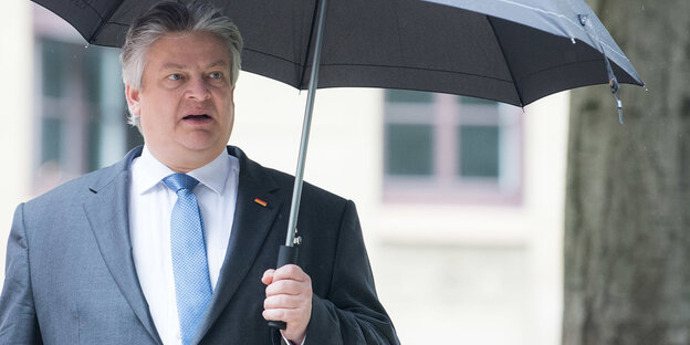 Thomas Seitz steht unter einem Baum mit Regenschirm in der Hand Thomas Seitz steht unter einem Baum mit Regenschirm in der Hand