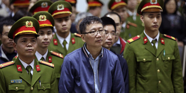 Trinh Xuan Thanh, vietnamesischer geschäftsmann und ehemaliger politiker steht umringt von vietnamesischen, uniformierten polizisten in einem gerichtssaal Trinh Xuan Thanh, vietnamesischer geschäftsmann und ehemaliger politiker steht umringt von vietnamesischen, uniformierten polizisten in einem gerichtssaal
