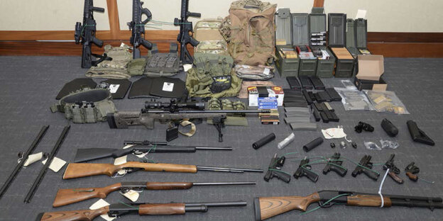Zahlreiche Schusswaffen und Munition liegen auf dem Boden aufgereiht Zahlreiche Schusswaffen und Munition liegen auf dem Boden aufgereiht