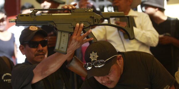 Mehrere Polizisten halten ein Maschinengewehr hoch Mehrere Polizisten halten ein Maschinengewehr hoch