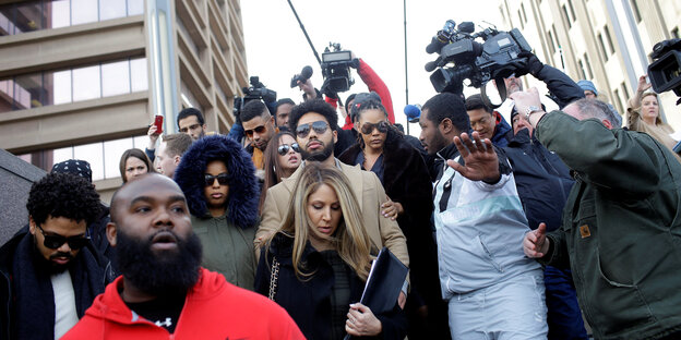 Eine Menschengruppe, in ihrer Mitte der Schauspieler Jussie Smollett, umringt von Kameras und Mikrofonen Eine Menschengruppe, in ihrer Mitte der Schauspieler Jussie Smollett, umringt von Kameras und Mikrofonen