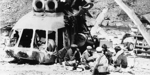 Afghanische Kämpfer essen neben einem zerstörten Helikopter Afghanische Kämpfer essen neben einem zerstörten Helikopter