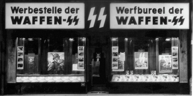 Schwarz-Weiß-Aufnahme: In einer Ladenfläche sind die Schriftzüge "Werbestelle der Waffen-SS" auf Deutsch und Belgisch zu sehen, im Schaufenster sind Bilder von SS-Angehörigen zu sehen Schwarz-Weiß-Aufnahme: In einer Ladenfläche sind die Schriftzüge "Werbestelle der Waffen-SS" auf Deutsch und Belgisch zu sehen, im Schaufenster sind Bilder von SS-Angehörigen zu sehen