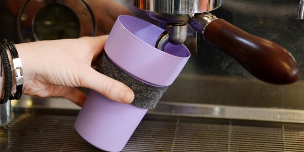 ein lilafarbener Plastikbecher unter einer Kaffeemaschine ein lilafarbener Plastikbecher unter einer Kaffeemaschine
