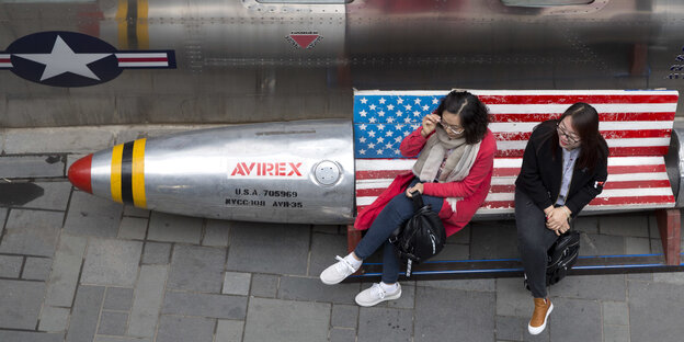 Zwei Frauen sitzen auf einer Bank, die mit der US Flagge dekoriert ist Zwei Frauen sitzen auf einer Bank, die mit der US Flagge dekoriert ist