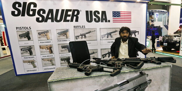 Ein Mann an einem Stand mit Waffen Ein Mann an einem Stand mit Waffen