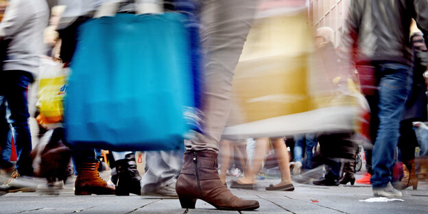 In einer Fußgängerzone sind viele Schuhe und Einkaufstaschen zu sehen In einer Fußgängerzone sind viele Schuhe und Einkaufstaschen zu sehen