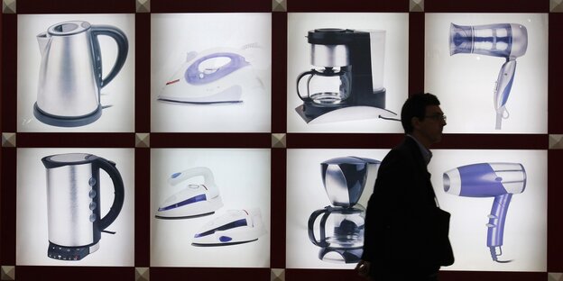 Ein Mensch läuft an einem Laden mit Elektrogeräten bei der chinesischen Import-Export-Messe vorbei Ein Mensch läuft an einem Laden mit Elektrogeräten bei der chinesischen Import-Export-Messe vorbei