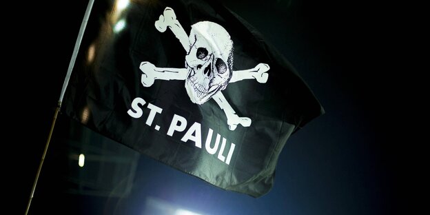 Eine schwarze Flagge mit weißem Totenkopf und "St Pauli"-Aufschrift Eine schwarze Flagge mit weißem Totenkopf und "St Pauli"-Aufschrift