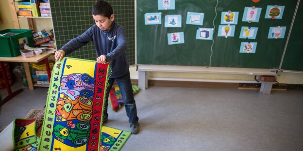 Ein Kind mit quietschbunten Gebetsteppichen in einem Klassenzimmer Ein Kind mit quietschbunten Gebetsteppichen in einem Klassenzimmer