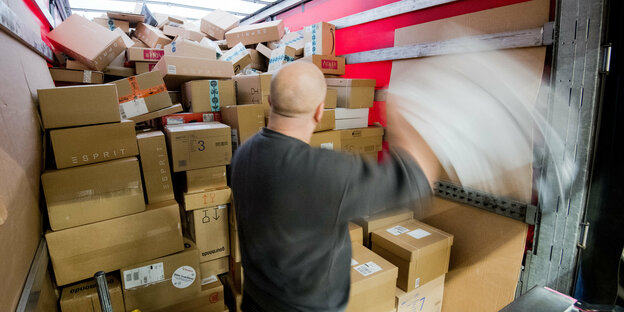 Ein Mann stapelt Pakete in einem Paketzentrum von Deutscher Post und DHL in den Laderaum eines LKWs