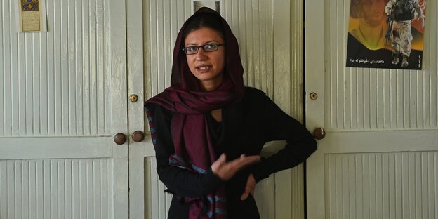 Eine junge Frau gestikuliert und spricht im Stehen während eines Interview Eine junge Frau gestikuliert und spricht im Stehen während eines Interview