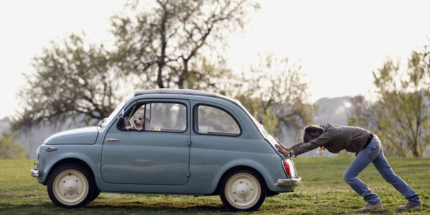 Eine Frau schiebt einen Fiat 500 Eine Frau schiebt einen Fiat 500