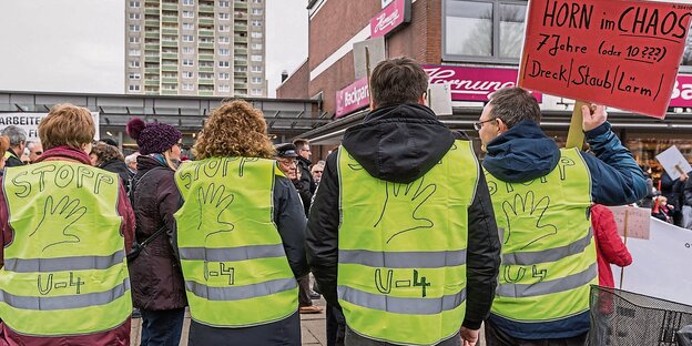 Vier Menschen in gelben Westen stehen am Rand der Demo