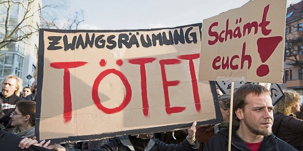 Demonstranten tragen ein Plakat mit der Aufschrift "Zwangsräumung tötet". Demonstranten tragen ein Plakat mit der Aufschrift "Zwangsräumung tötet".