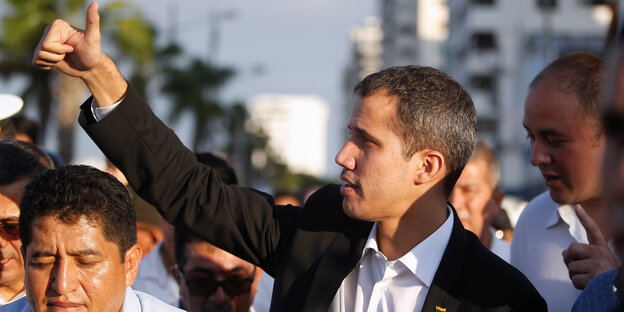 Ein Mann mit sehr kurzen Haaren, Juan Guaido, steht inmitten von Menschen und hält den Daumen nach oben Ein Mann mit sehr kurzen Haaren, Juan Guaido, steht inmitten von Menschen und hält den Daumen nach oben